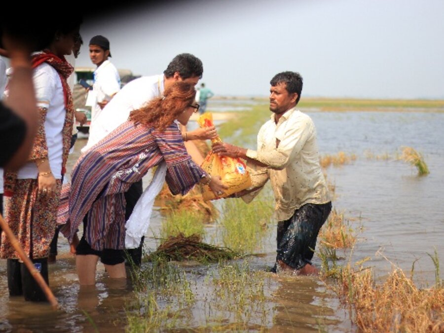 Relief bag handed to a flood-affected farmer standing in water